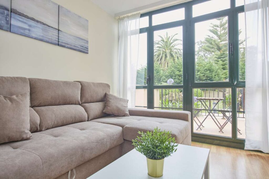 Salón con sofá, mesa de centro y puerta acristalada a la terraza con vistas a jardín