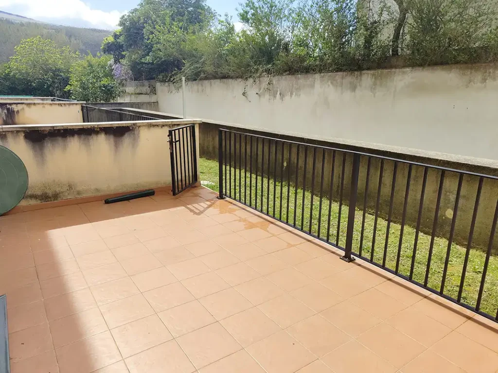Terraza embaldosada con barandilla de forja y vistas a un jardín comunitario en el apartamento Apartagal de San Miguel, Barreiros