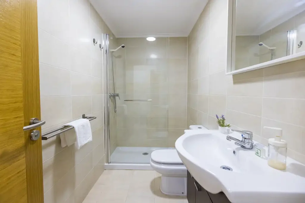 Baño con ducha de obra acristalada, mueble bajolavabo y espejo en un apartamento de Apartagal en Foz
