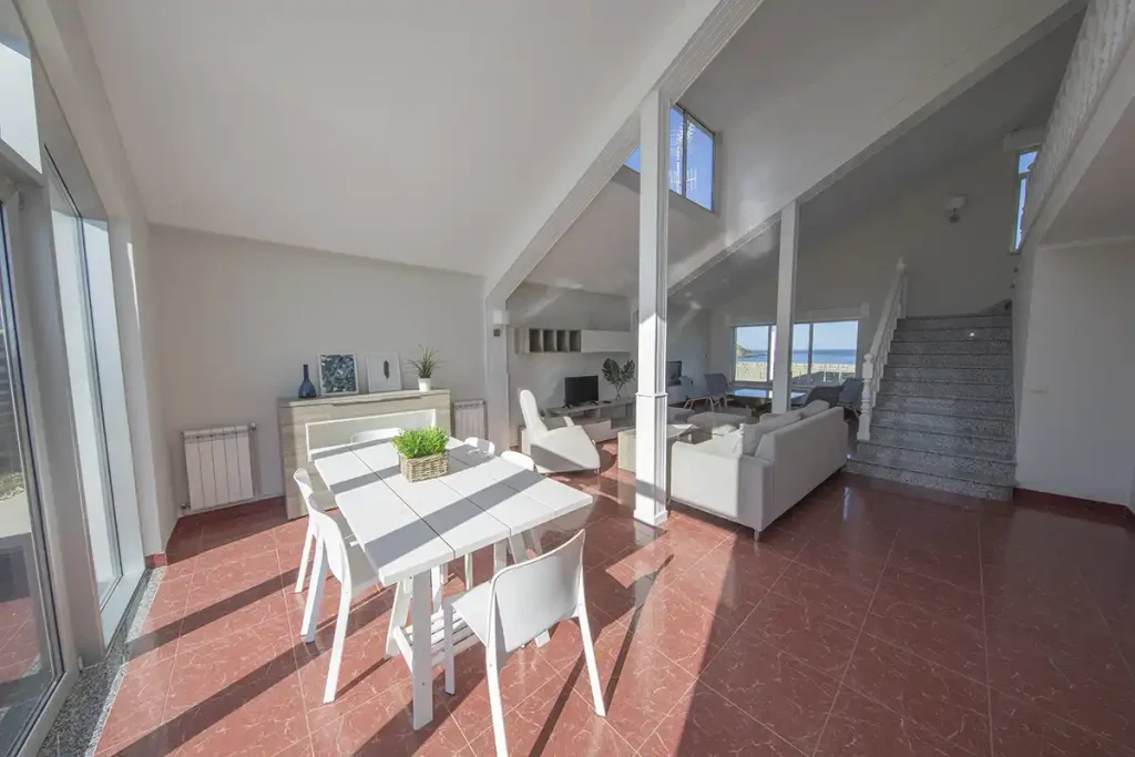 Salón comedor luminoso de un apartamento Apartagal en Foz, con escalera y vistas al mar