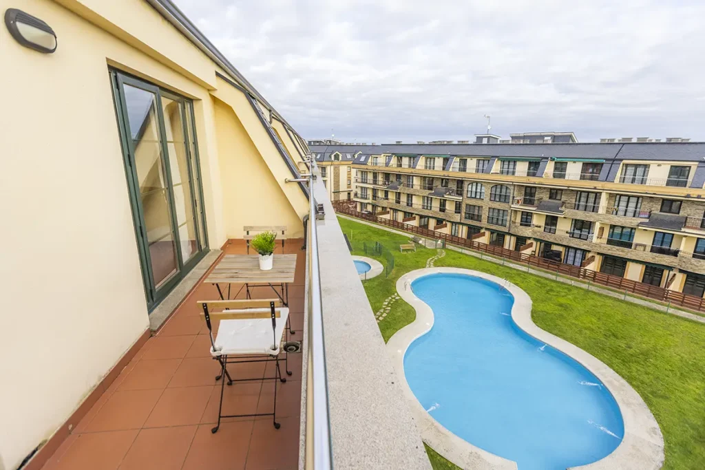 Terraza de un ático en Barreiros con mesa, sillas y vista a la piscina y el jardín comunitario
