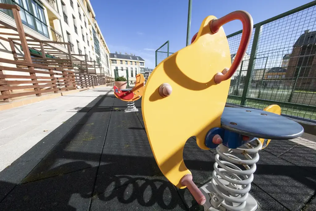Columpio de muelle amarillo sobre suelo de caucho en el parque infantil de Apartagal en Foz