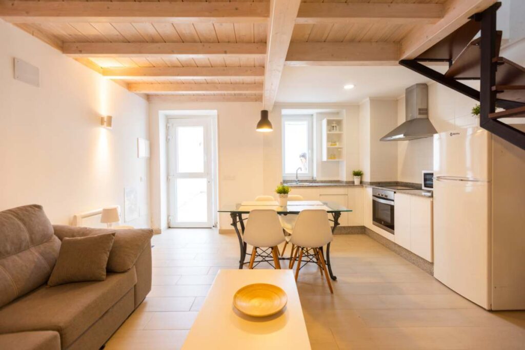 Salón abierto a cocina y comedor con vigas de madera vistas y escalera, apartamento de Apartagal