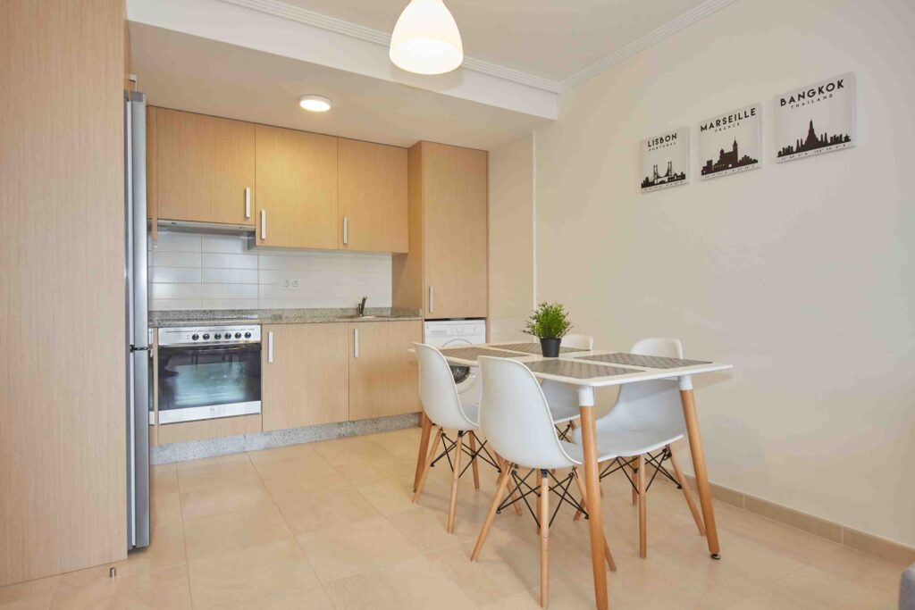 Cocina equipada con mesa comedor y sillas blancas en el apartamento San Miguel de Apartagal