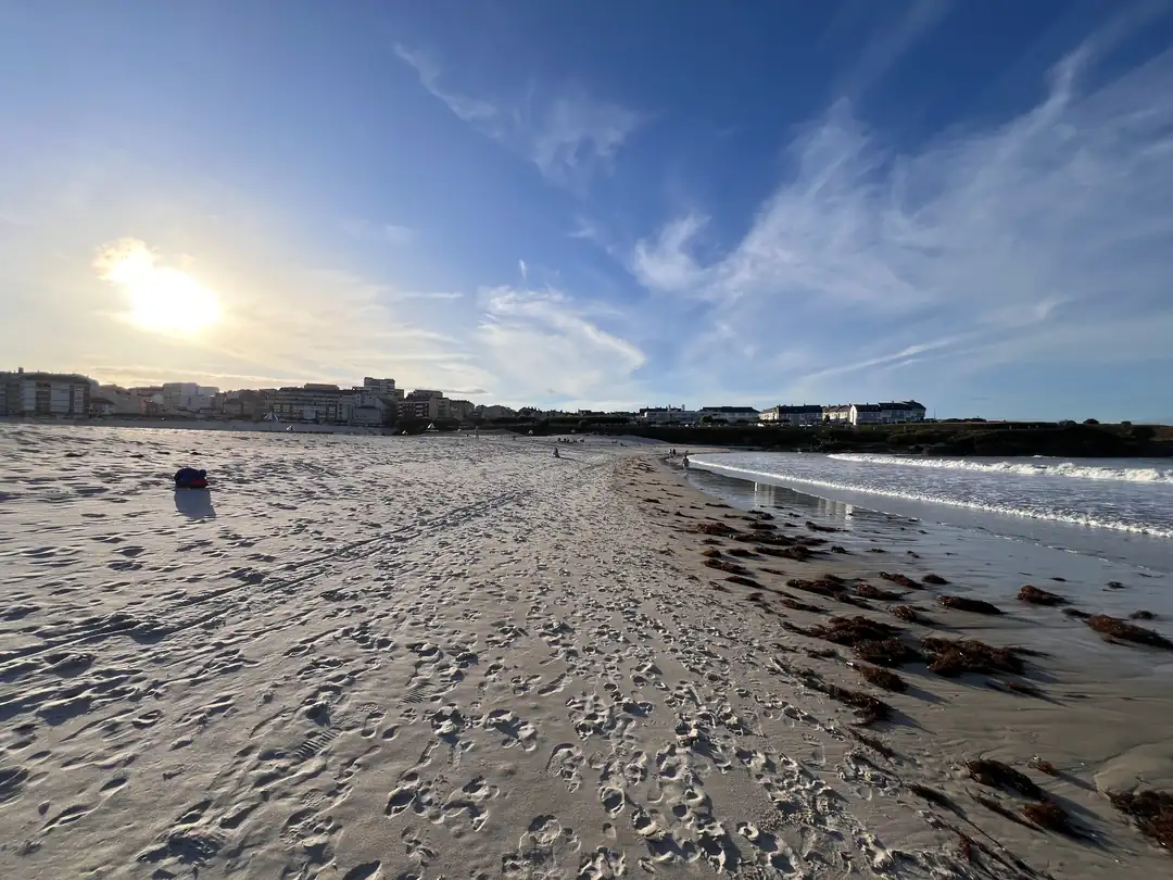 Playa de A Rapadoira, Foz Arenal de A Rapadoira en Foz con el pueblo al fondo y el sol bajo