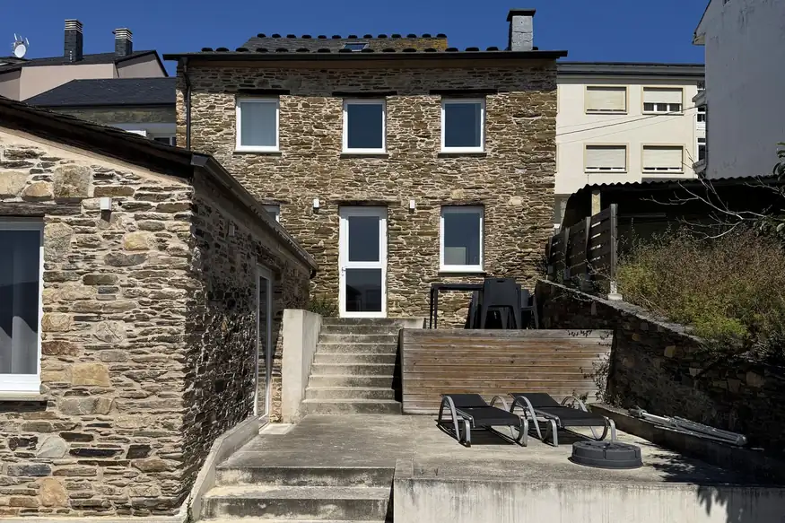 Casa de piedra de Apartagal con terraza de madera, tumbonas y escalera de acceso en la costa de Lugo