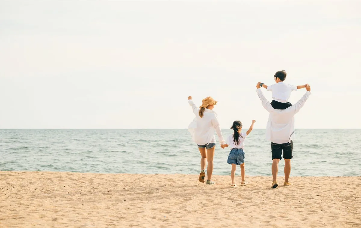 Familia con dos niños paseando por la orilla de una playa tranquila de Galicia