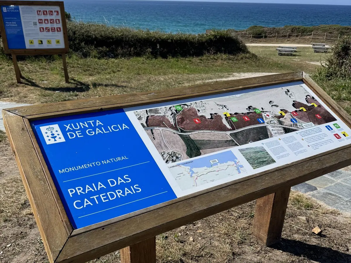 Panel informativo de la Xunta del Monumento Natural Praia das Catedrais con el mar al fondo